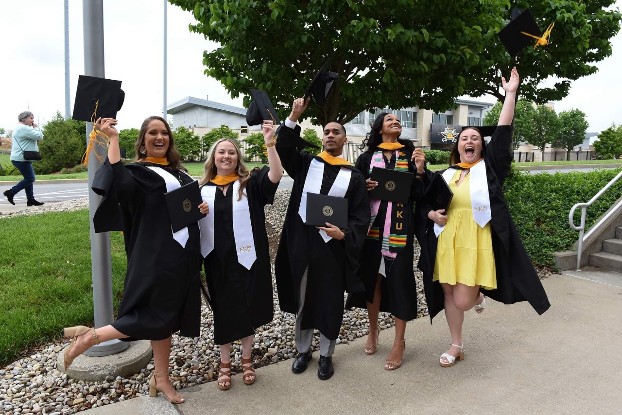 Group of graduated students celebrating and tossing their caps into the air